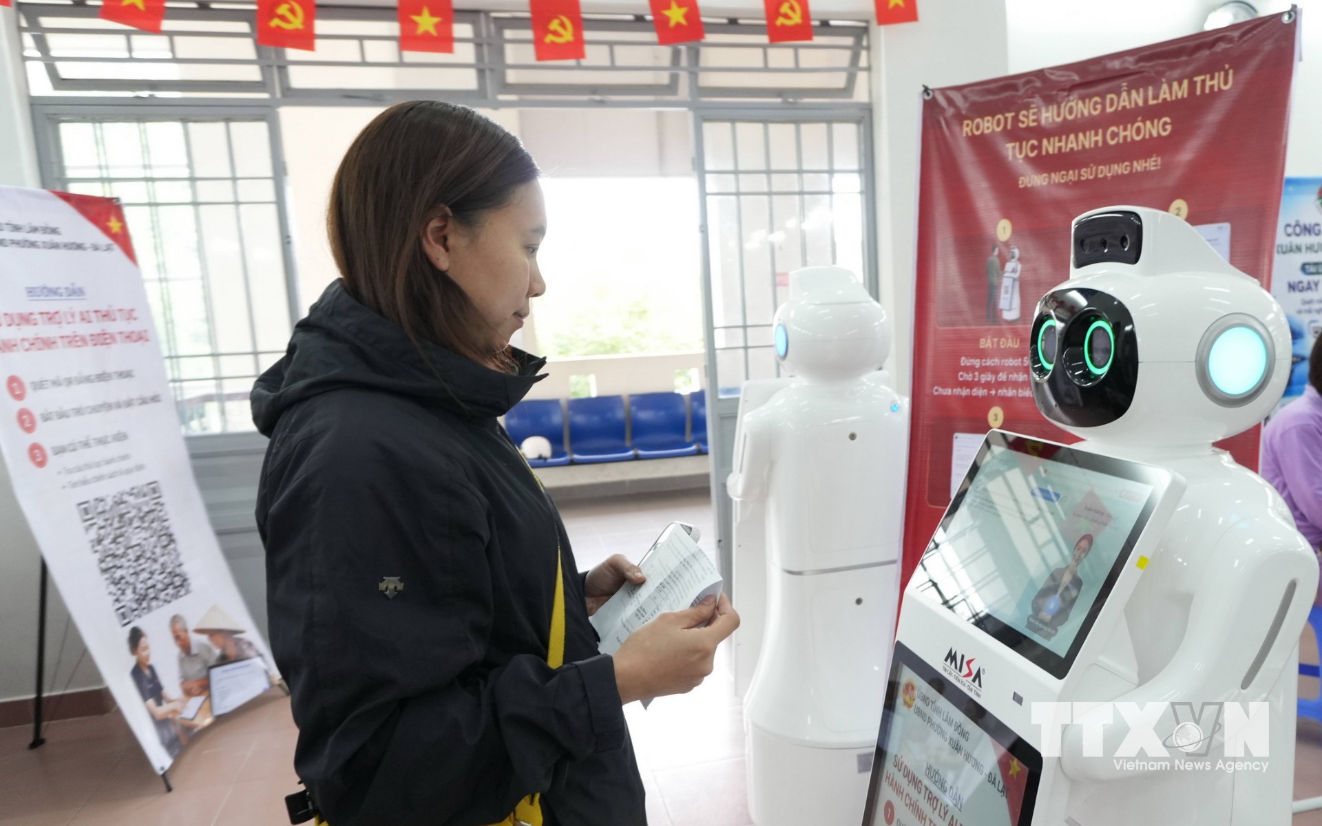 Người dân trao đổi với robot AI để được hướng dẫn thủ tục hành chính tại Trung tâm Phục vụ hành chính công phường Xuân Hương – Đà Lạt (Lâm Đồng). (Ảnh: Nguyễn Dũng/TTXVN)